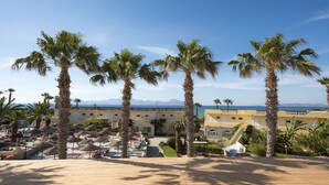 Un complexe hôtelier doté de palmiers, d’une piscine et offrant une vue sur la mer.