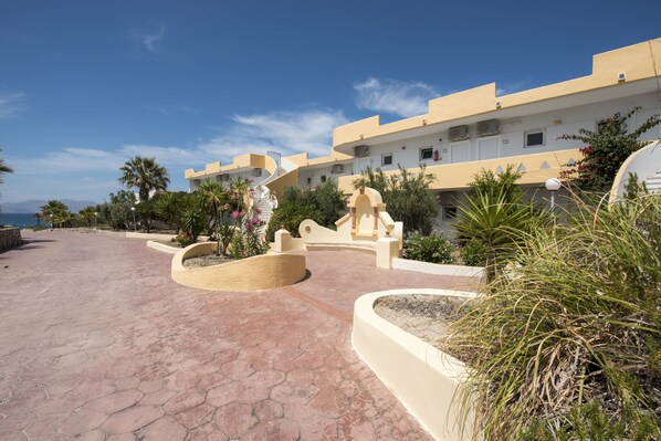 A resort with a paved walkway, palm trees, and a building with a curved facade.