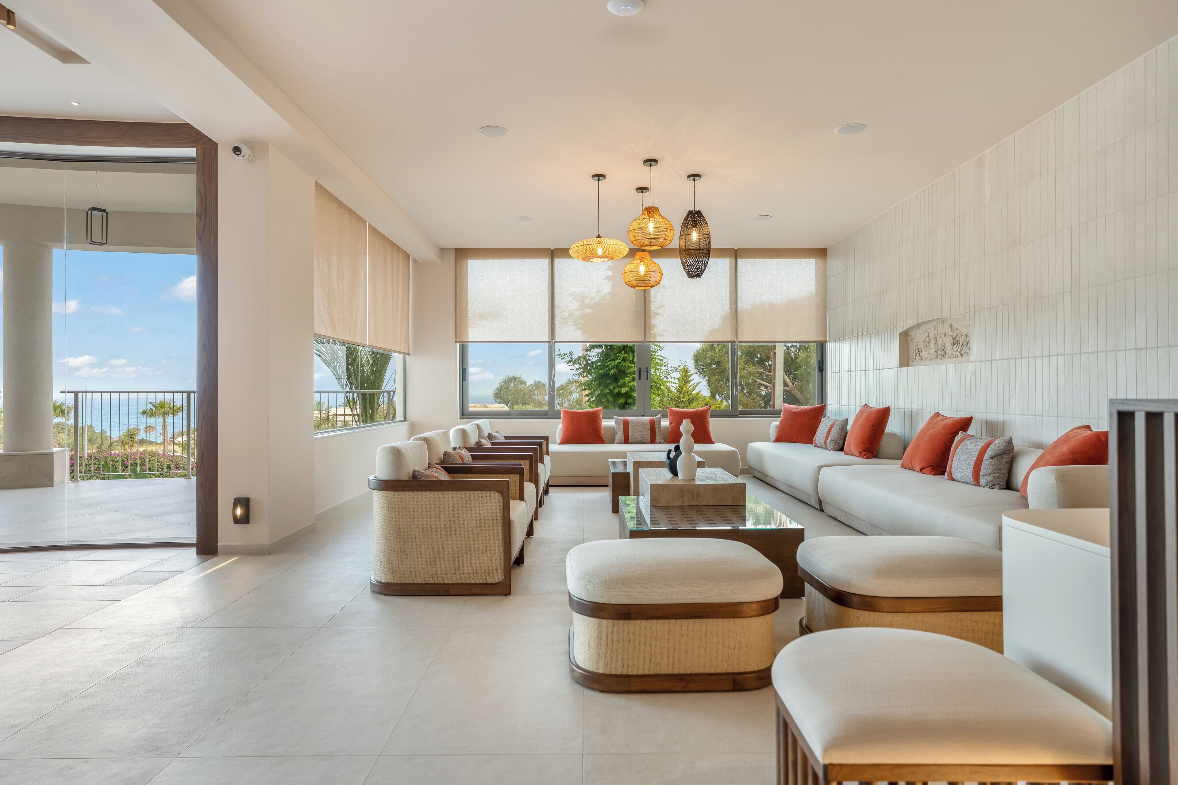 A modern living room with a sofa set, ottomans, a coffee table, and pendant lights.