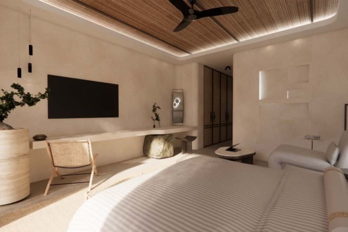 Un dormitorio moderno con una cama grande, un escritorio con una silla, un ventilador de techo y una planta grande en maceta.