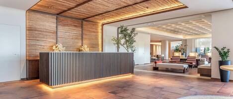 Ein moderner Empfangsbereich mit Holzboden, einer Rezeption und einer Sitzecke mit Sofas und einem Couchtisch.