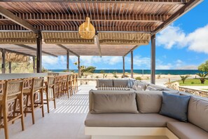 A covered outdoor seating area with a view of the ocean, a bar, and a sofa. - Kouros Palace Active Lifestyle Hotel (Kos)