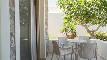 A balcony with a table and chairs, a potted plant, and a tree.