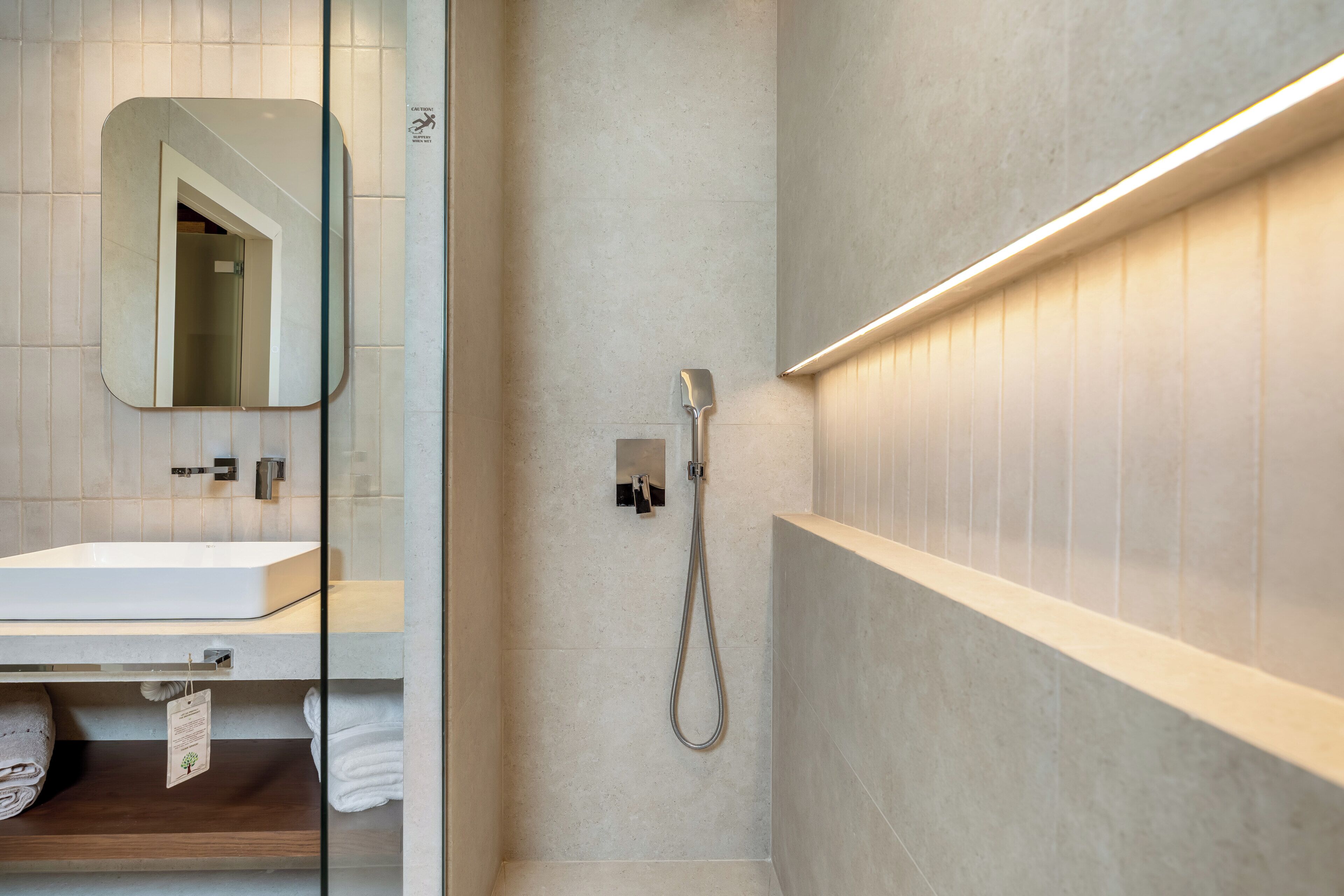 Une salle de bain moderne avec une douche à parois de verre, un lavabo blanc et un miroir.