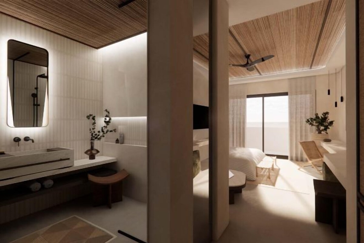 Una habitación de hotel moderna con una cama grande, un baño separado con tocador y un ventanal que proporciona luz natural.