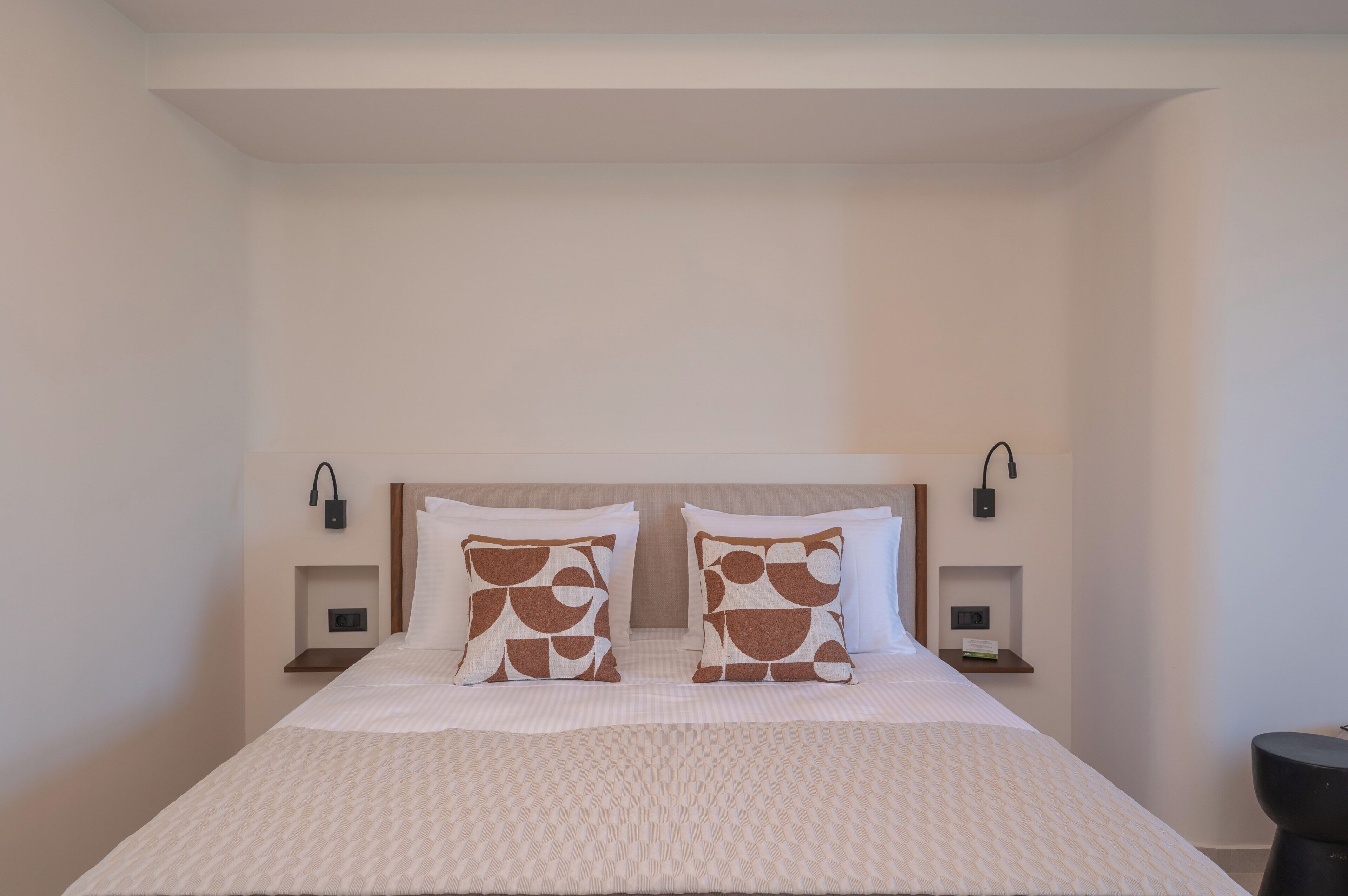 Una habitación de hotel con una cama grande, dos mesitas de noche y un cabecero.