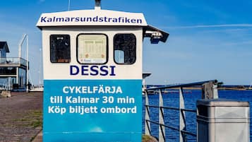 Ein kleines blaues und weißes Gebäude mit Kreuz darauf, beschriftet mit „DESSI“ und „Fähre für Fahrräder nach Kalmar, 30 Minuten. Fahrkarten an Bord erhältlich.“