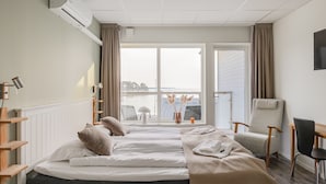 Et hotelværelse med en stor seng, en stol, et skrivebord og havudsigt.