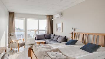 Et hotelværelse med en seng, en sofa, en stol, et lille bord og et vindue med gardiner.