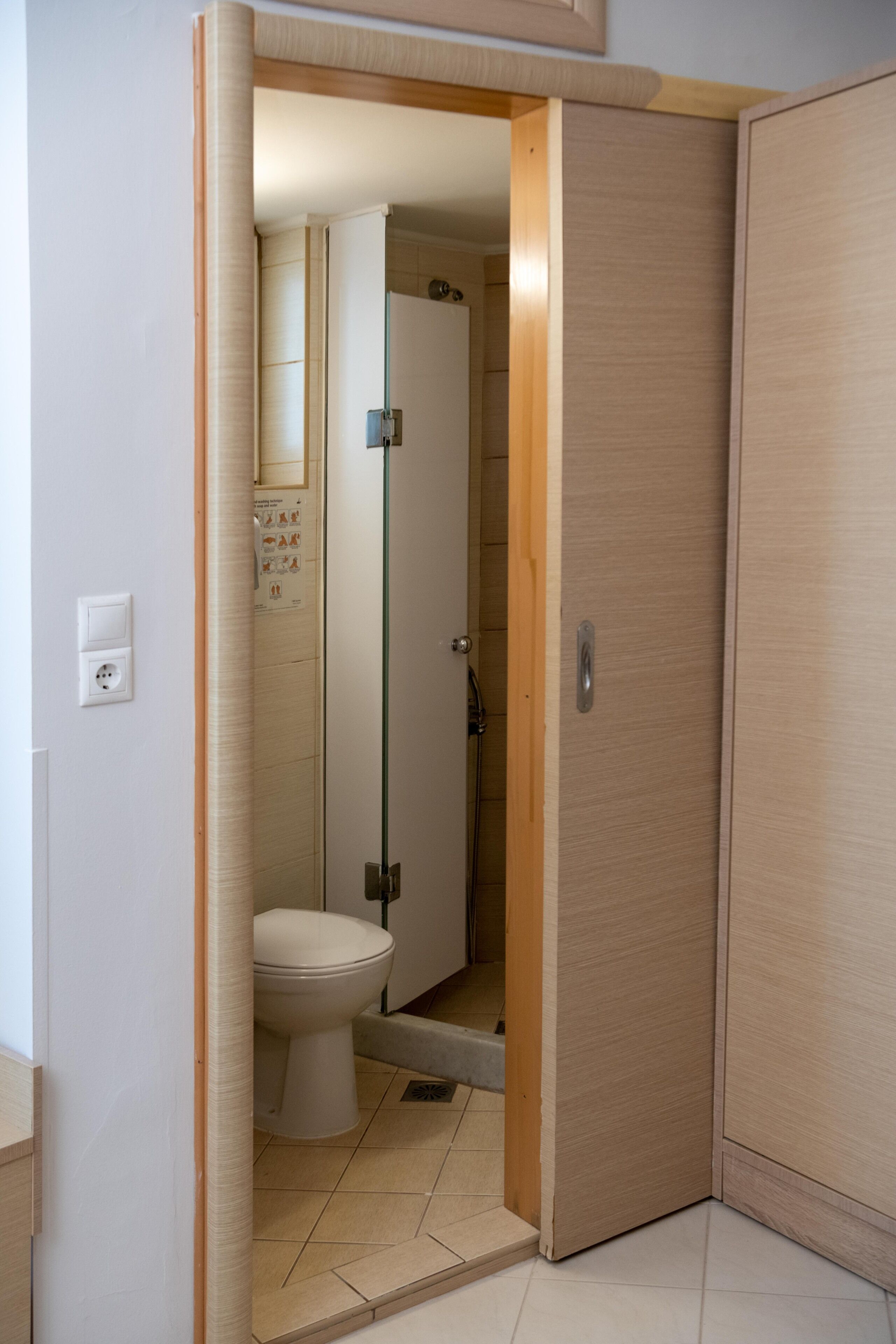 Un baño con inodoro, ducha y puerta de madera.