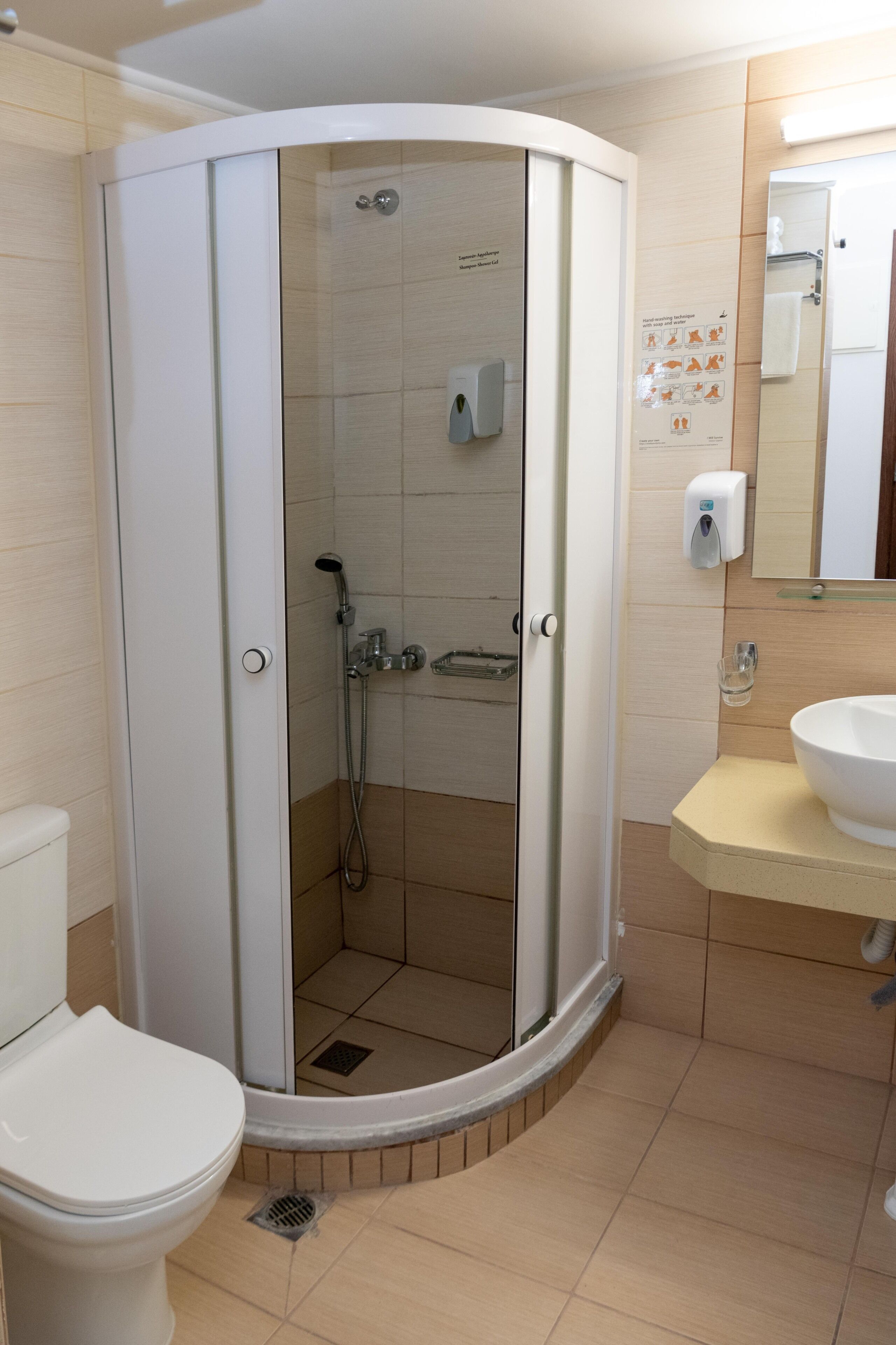 Un baño moderno con ducha de vidrio, inodoro y lavamanos con espejo.