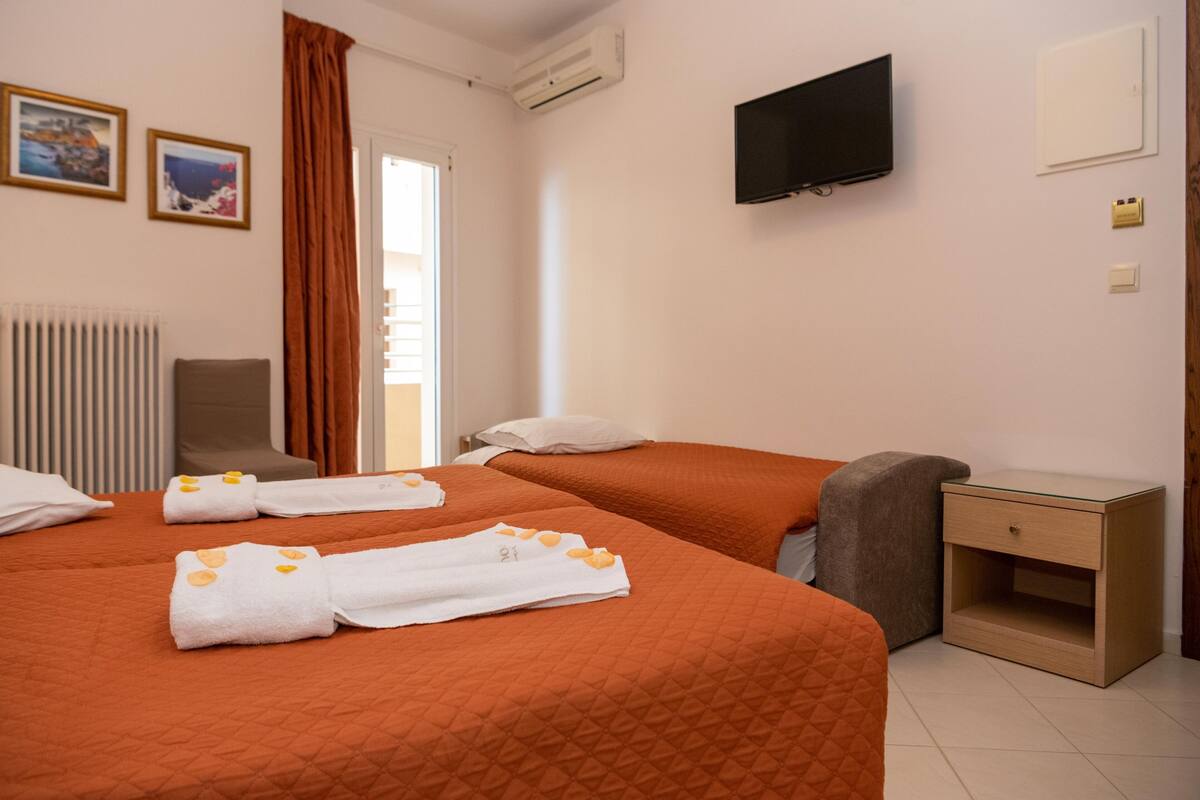 Une chambre d’hôtel avec deux lits, une télévision, une chaise et une petite table de chevet.