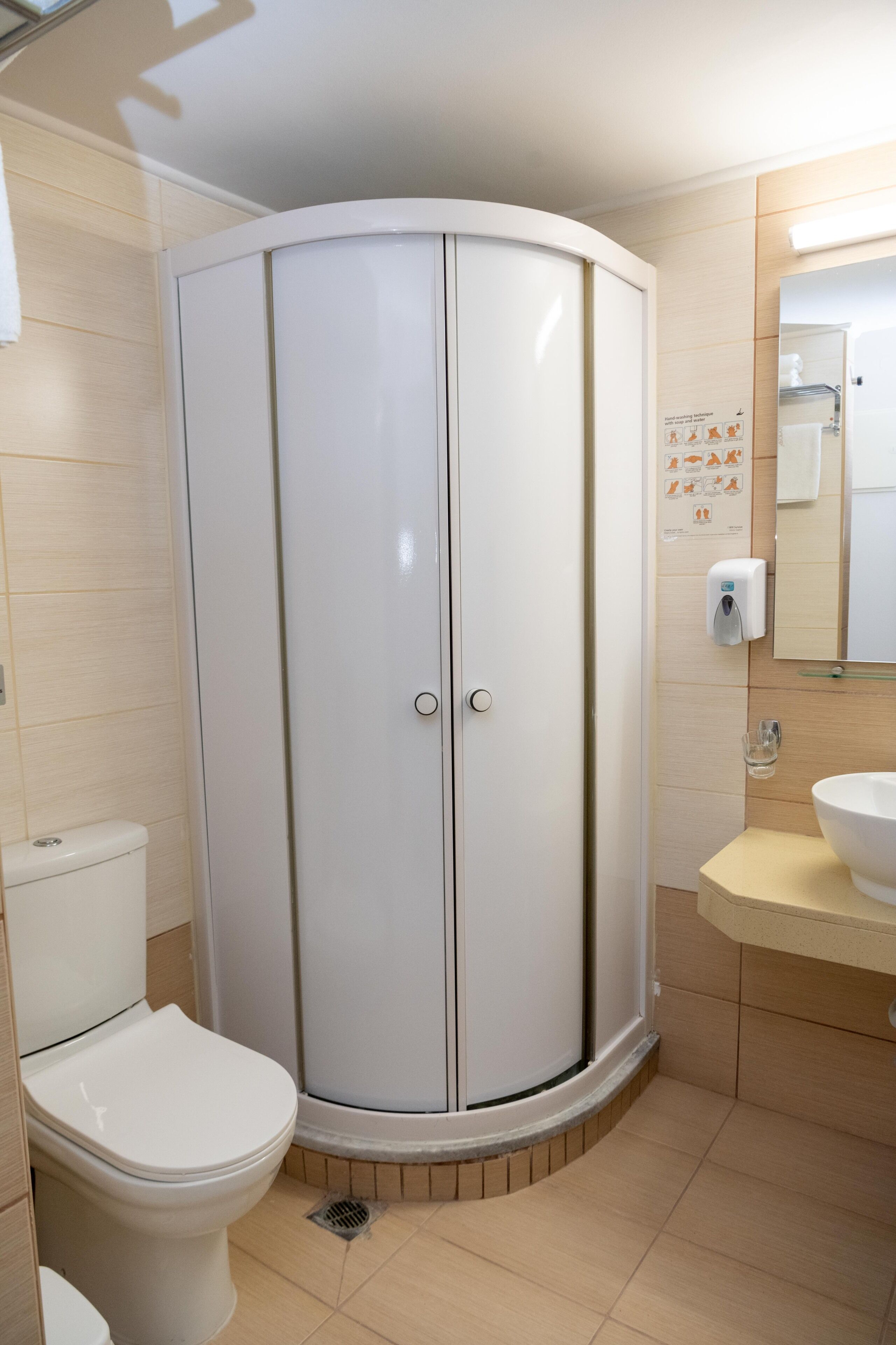 A bathroom with a white toilet, a sink with a mirror, and a shower enclosure.