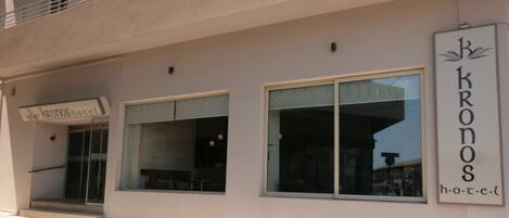 A hotel named "Kronos Hotel" with a modern facade, large windows, and a visible entrance.