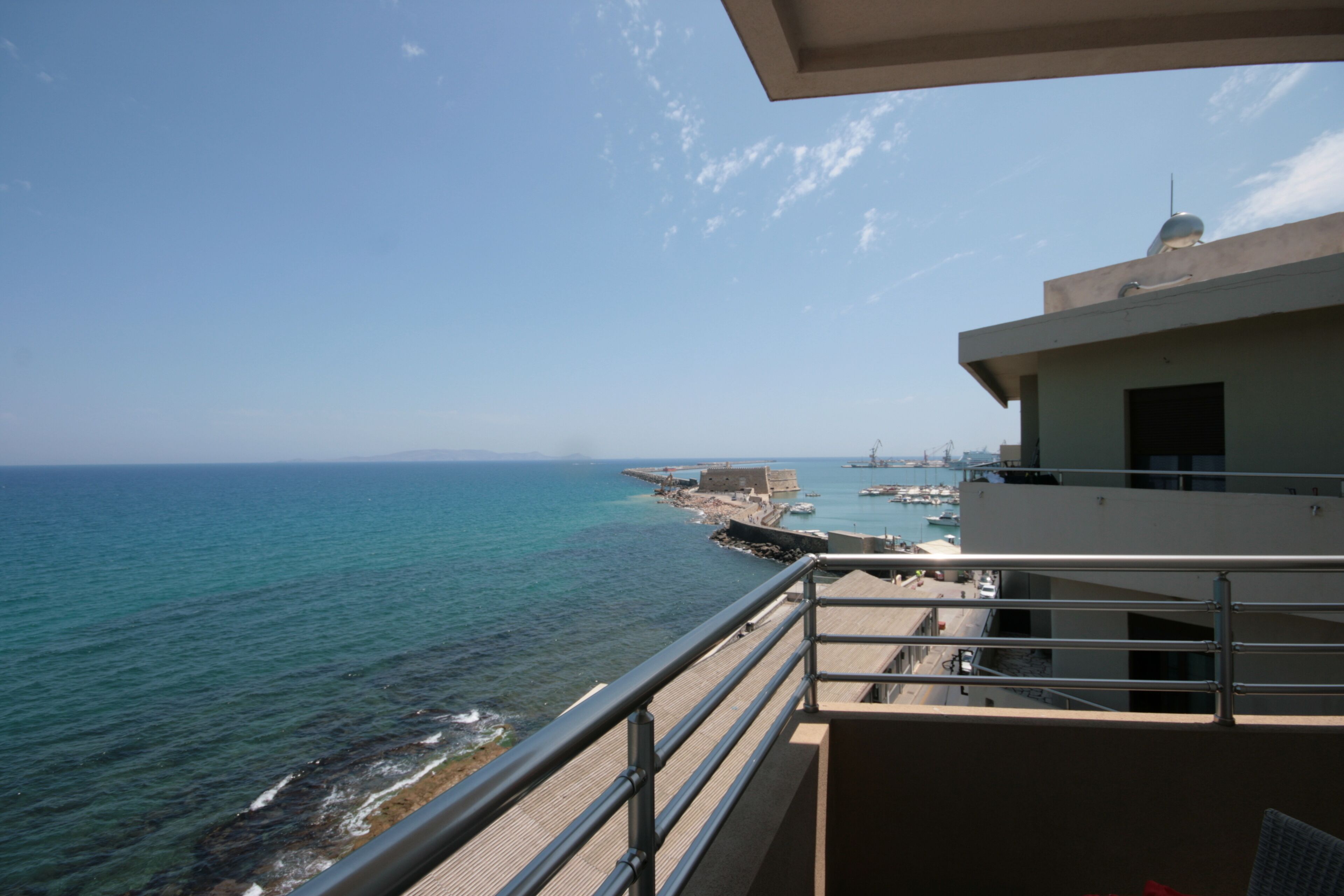 Un balcón con vista al mar y un muelle distante.