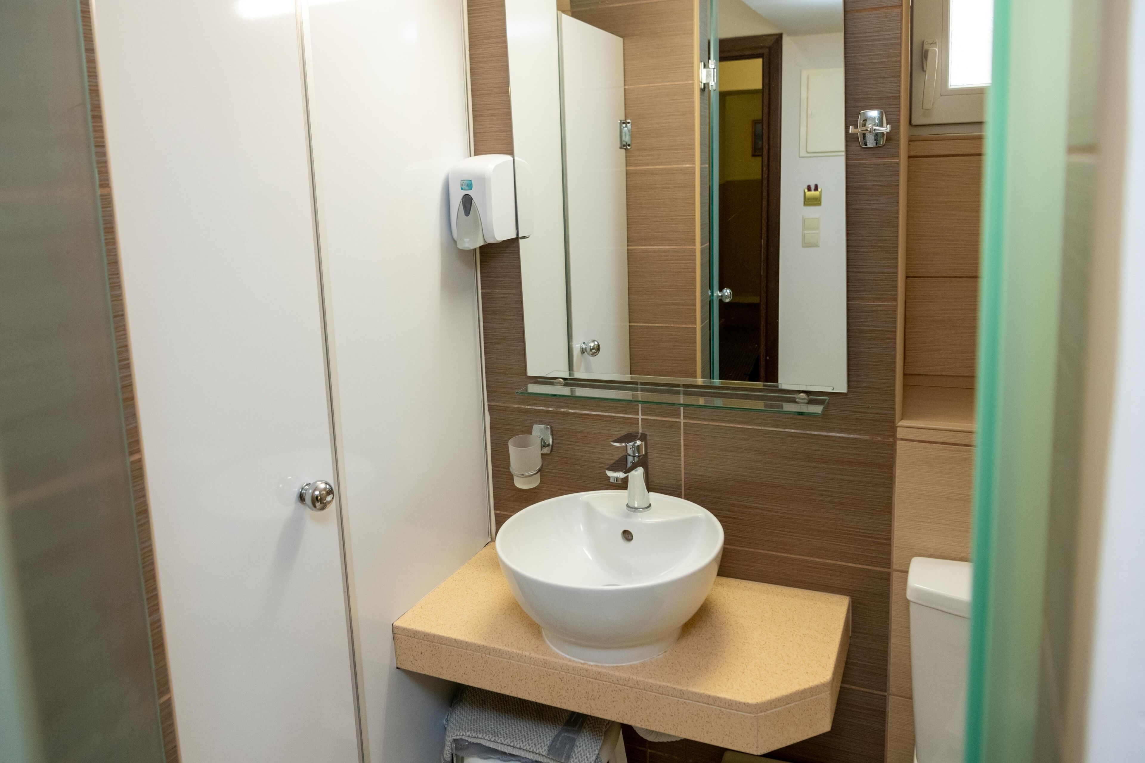 Un baño con un lavamanos blanco, un espejo y un dispensador de jabón.