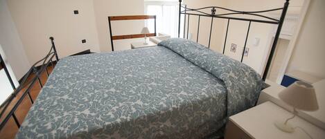 Un dormitorio con cama, mesita de noche y ventana.
