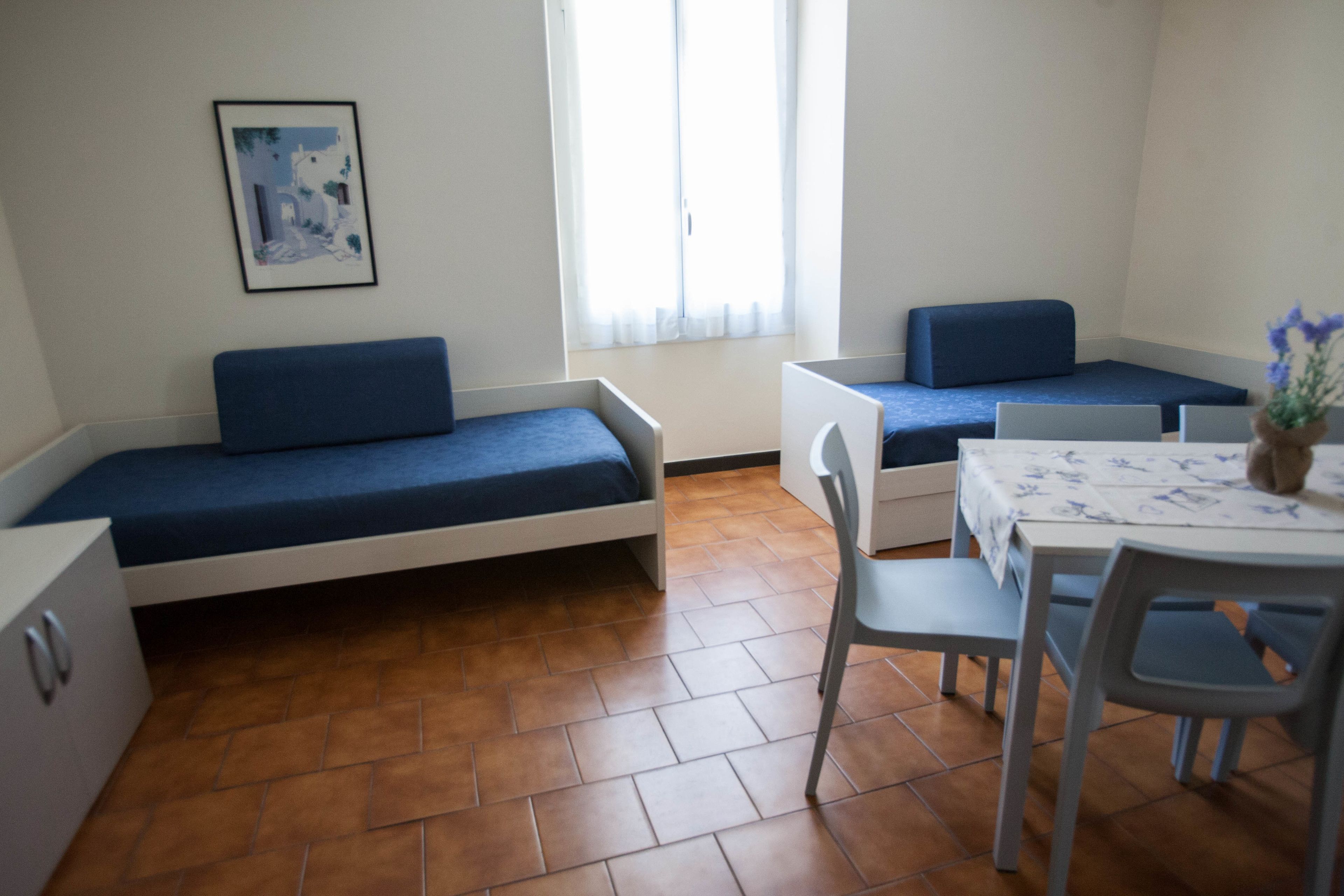 Una habitación pequeña y luminosa con una cama, un escritorio y una silla.