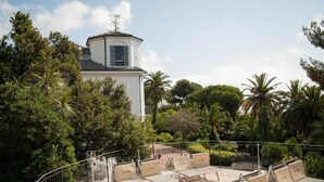 A white building with a small tower and a balcony with sun loungers. - Residence RTA Villa Marina (Imperia)