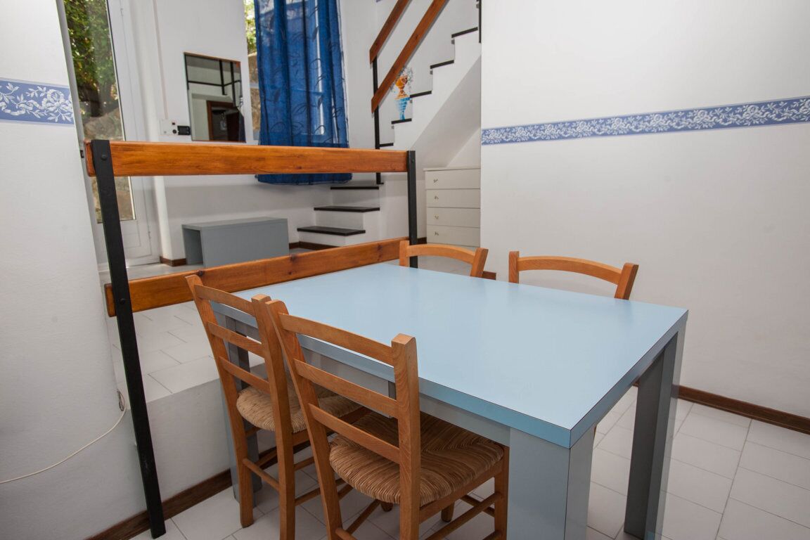 Un'area pranzo con tavolo e sedie, una scala e vista all'esterno.