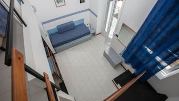 A room with a bed, a small table, a window with a curtain, and a staircase.