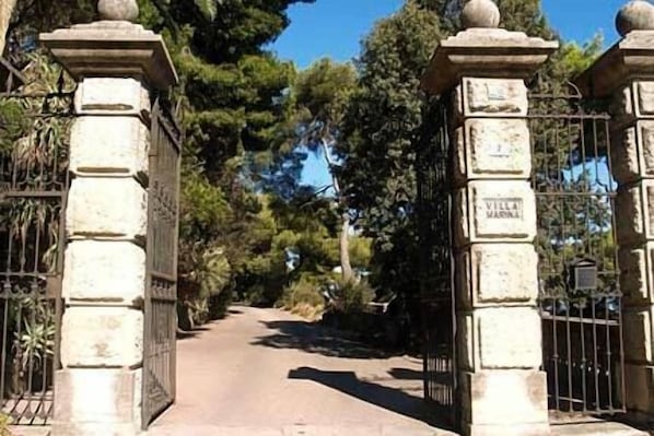Un chemin de pierre qui traverse un portail orné d’inscriptions, le tout étant entouré d’arbres.