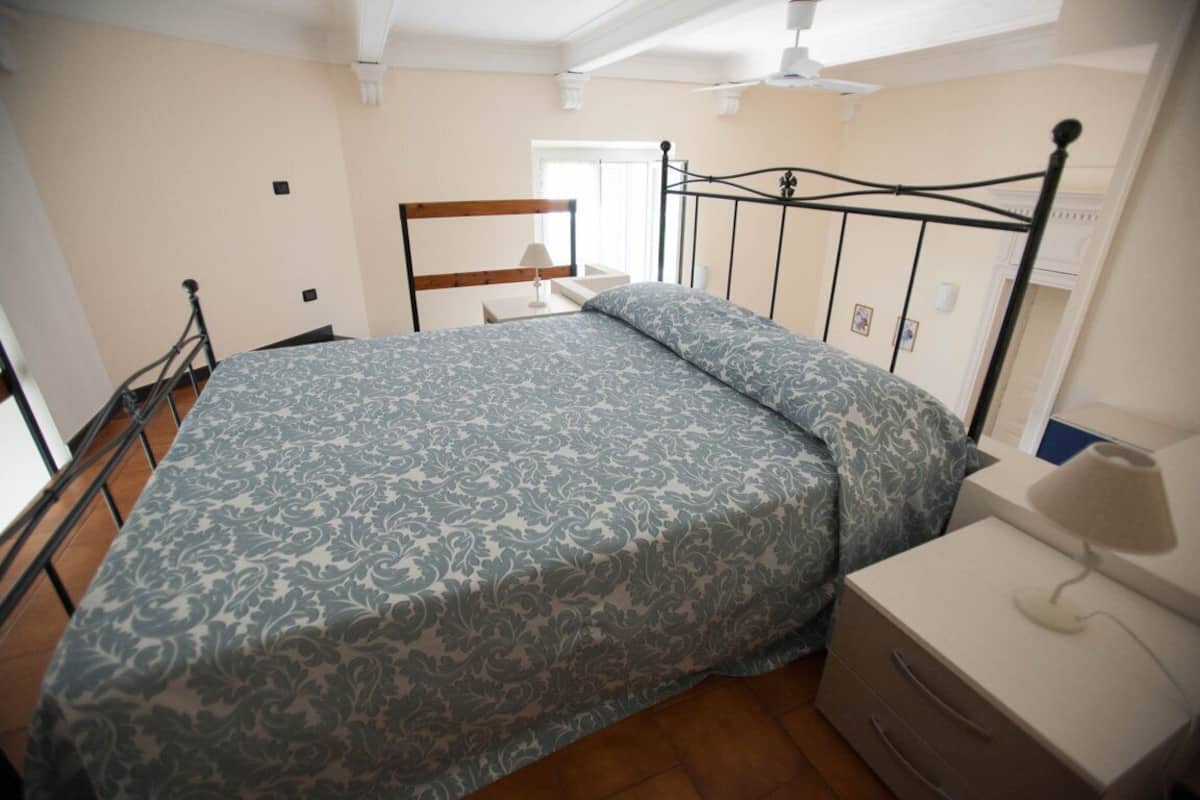 Un dormitorio con cama, mesita de noche y velador.