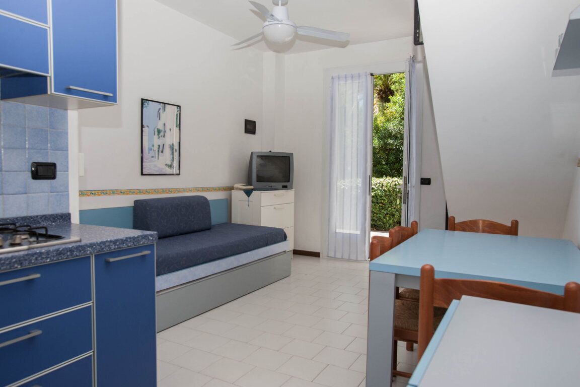 A compact room with a kitchenette, a bed, a TV, and a dining area.
