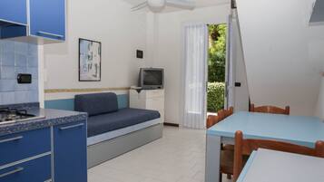 A compact room with a kitchenette, a bed, a TV, and a dining area.