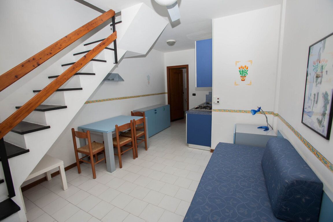 Un espace de vie compact comprenant un escalier, une kitchenette, un coin repas et un canapé.
