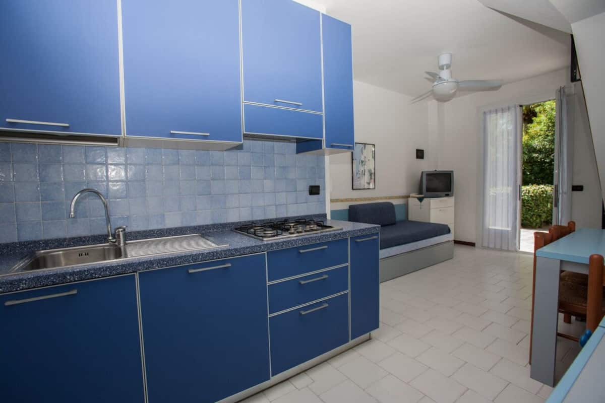 Una cocina moderna con armarios azules, estufa a gas y lavamanos.