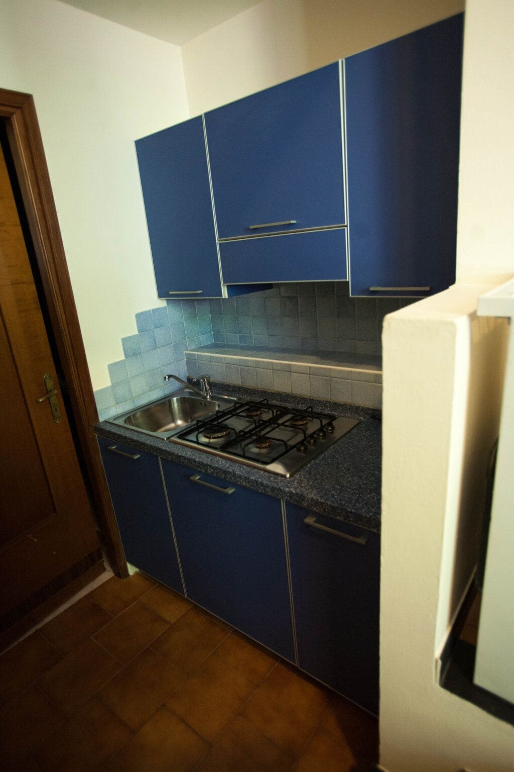 Une cuisine avec des armoires bleues, une cuisinière à gaz et un évier en acier inoxydable.