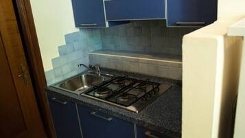 Une cuisine avec des armoires bleues, une cuisinière à gaz et un évier en acier inoxydable.