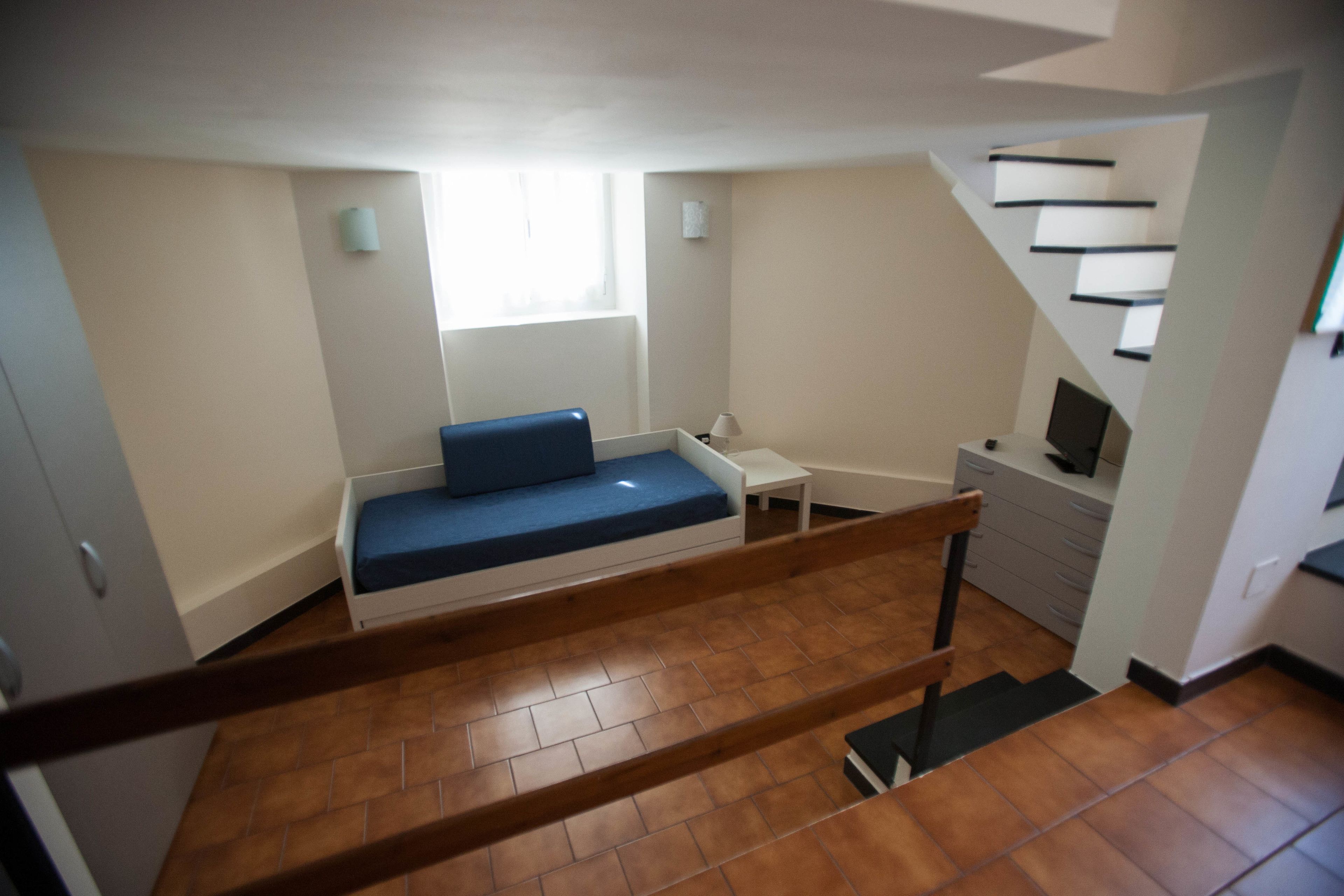 Une petite chambre comprenant un lit, un petit bureau, une chaise et un téléviseur.