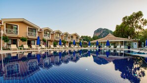 Un hotel con piscina, múltiples sillas de descanso y sombrillas.