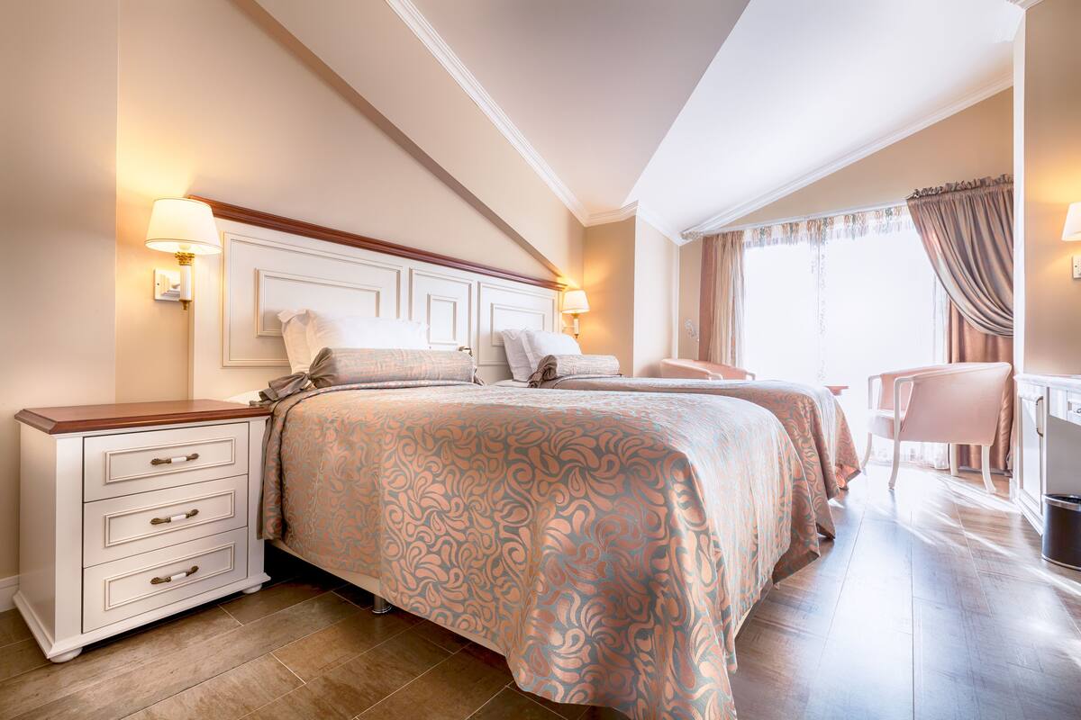 Ein Hotelzimmer mit einem großen Bett, einem Nachttisch, einem Sessel und einem Schreibtisch.