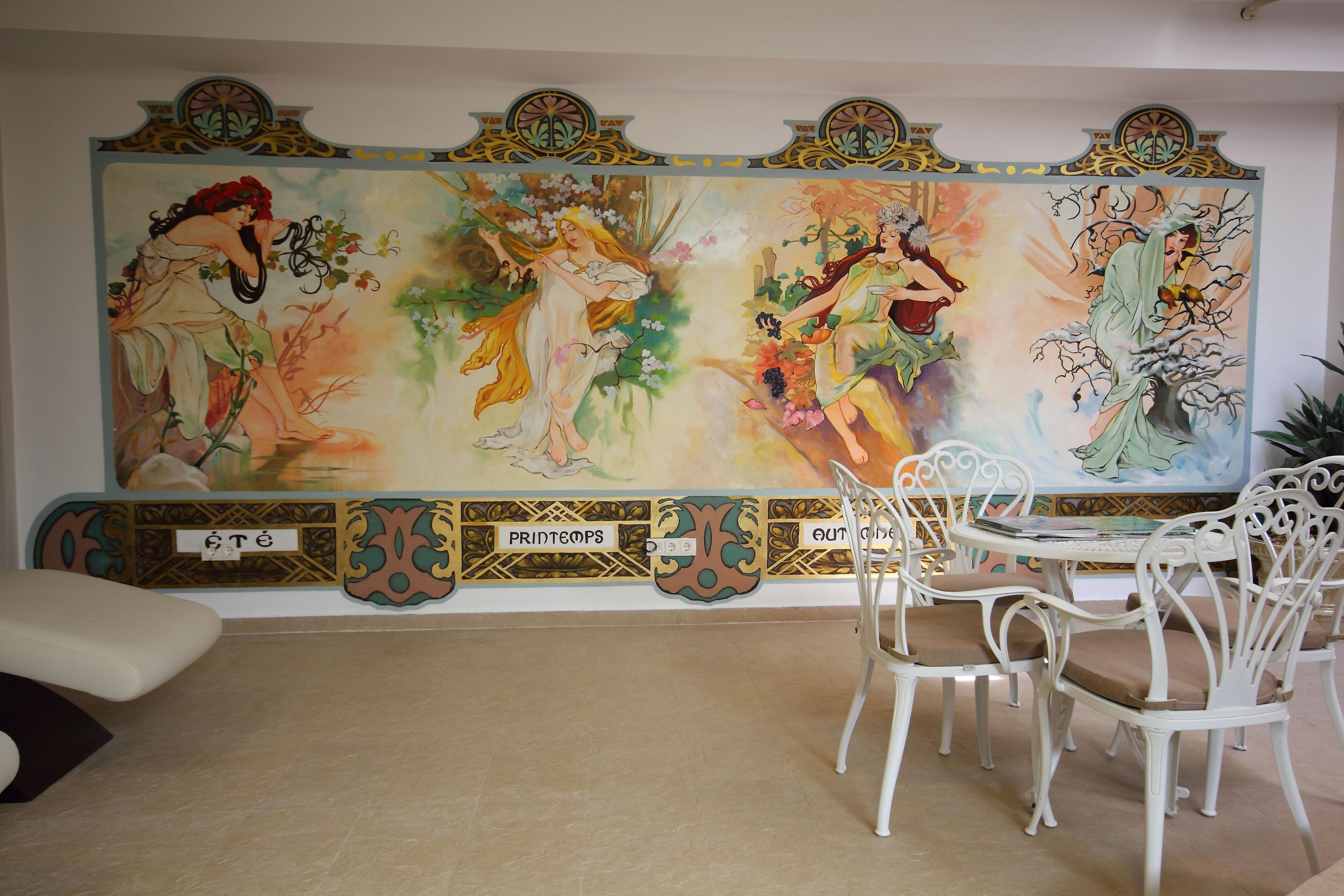 Comedor con un mural, sillas blancas y una mesa.