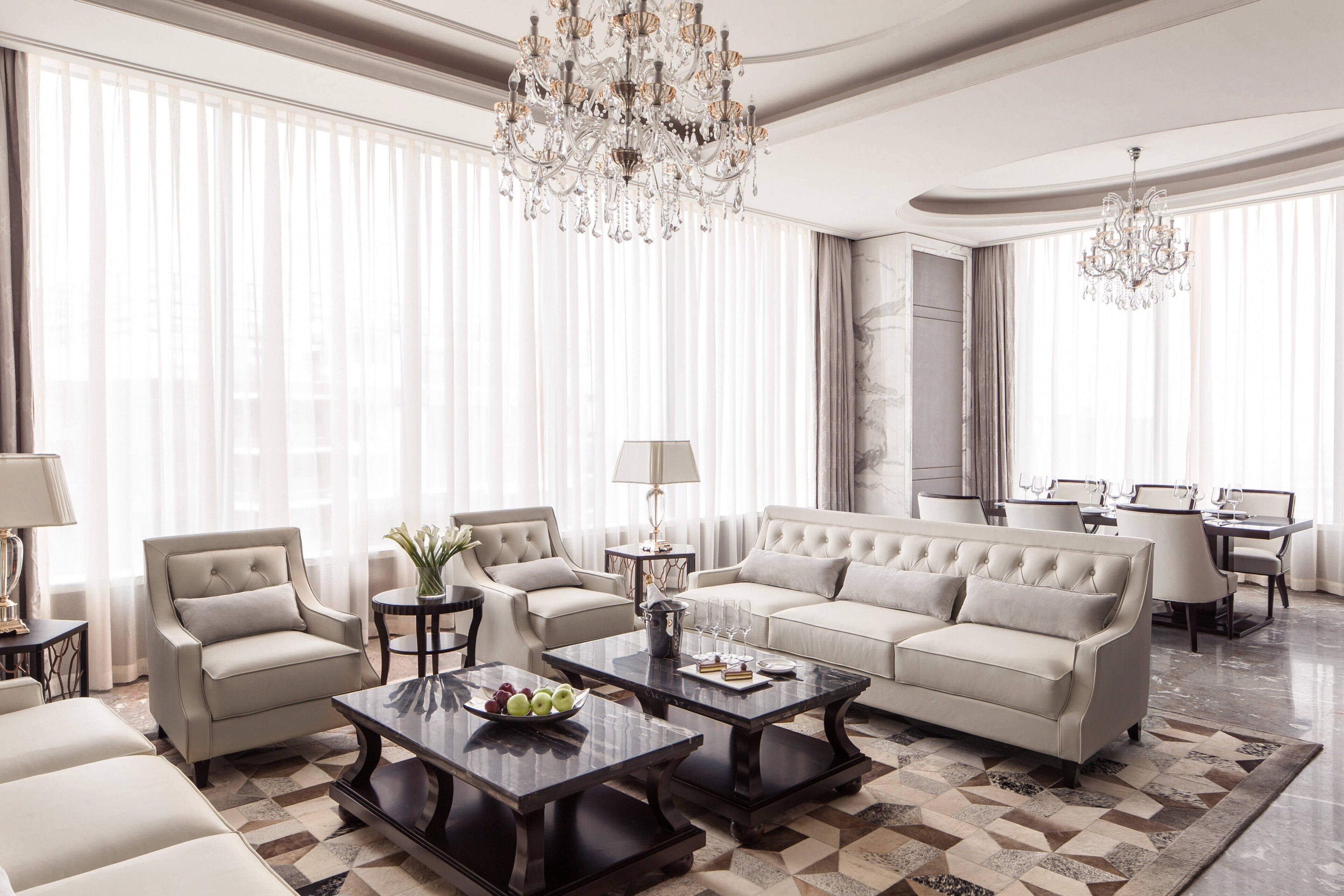 A spacious living room with a large sofa, two armchairs, a coffee table, and a chandelier.