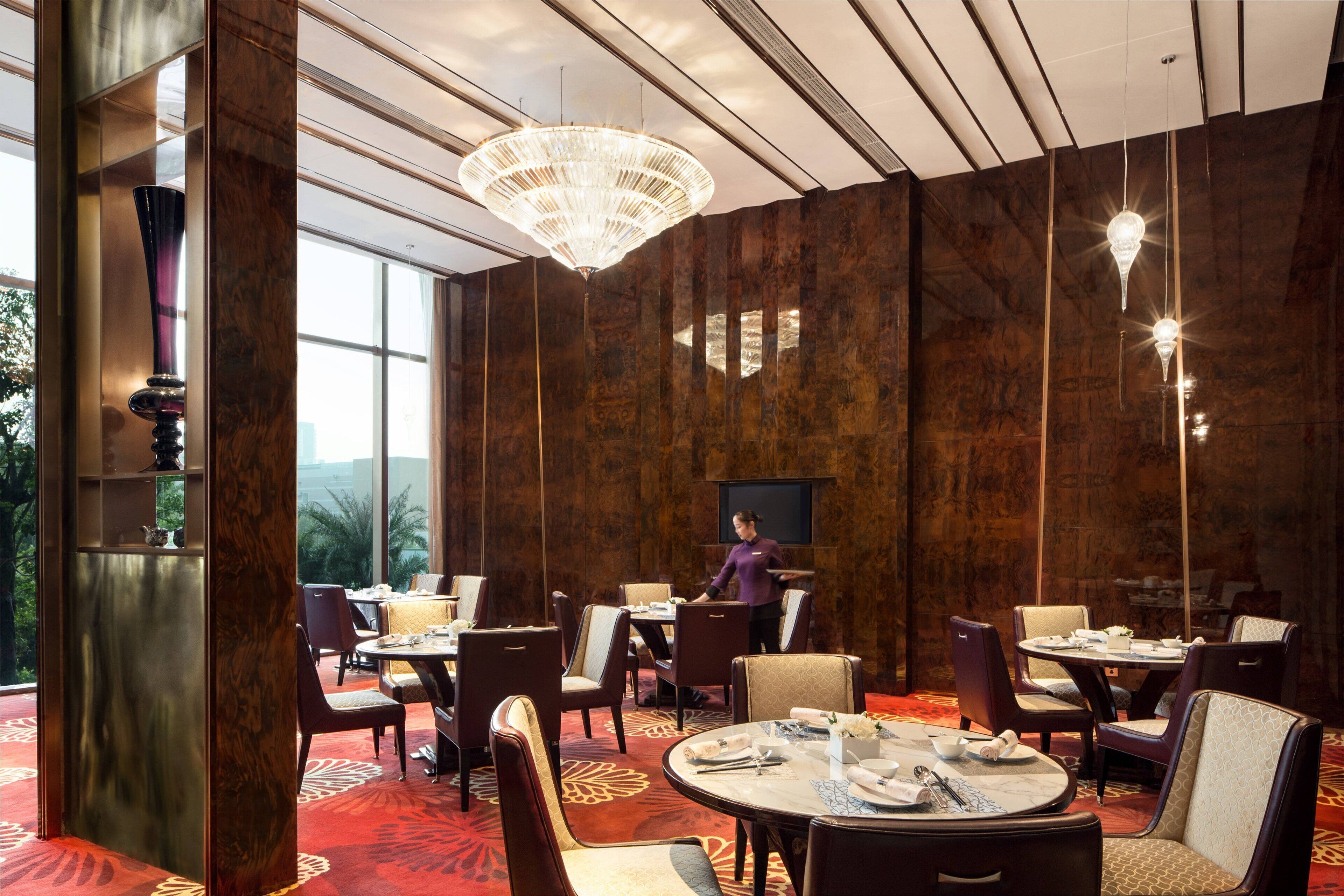 Un restaurant avec des tables rondes, des chaises et un grand lustre.