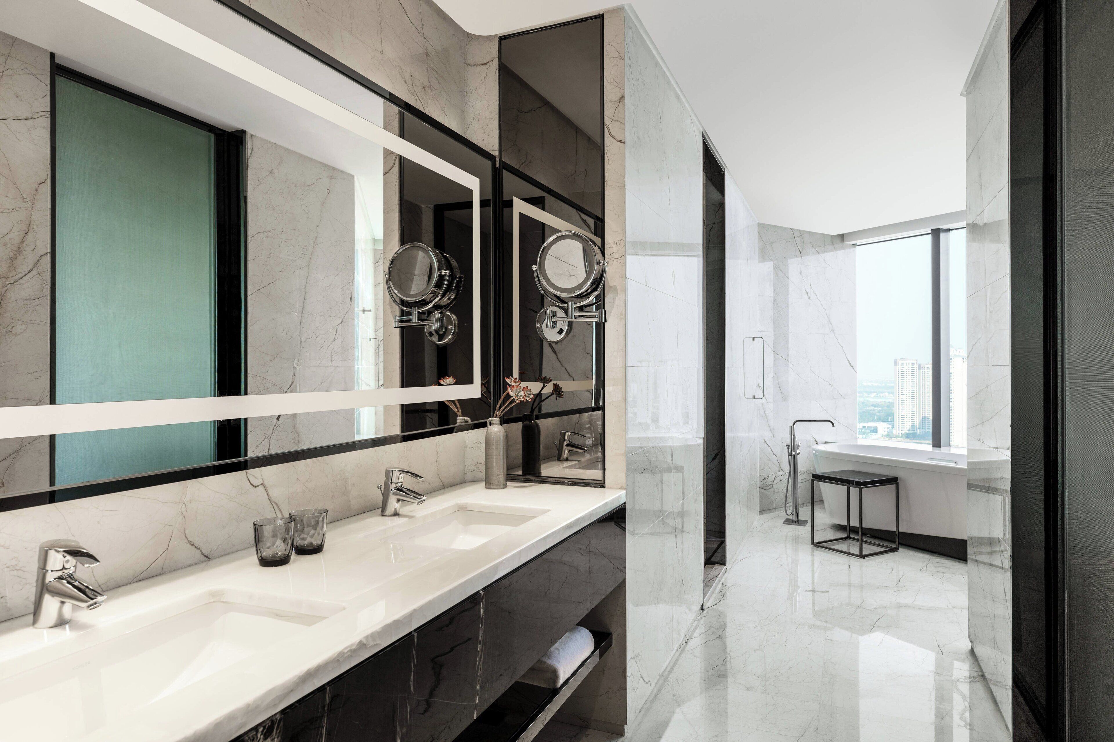 Un baño moderno con dos lavamanos, un espejo grande y una ventana.