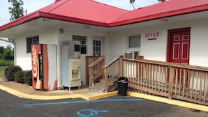 A building with a red roof, a Coca-Cola vending machine, an ice machine, and a wheelchair-accessible parking space. - Ole English Inn (Tuscaloosa)
