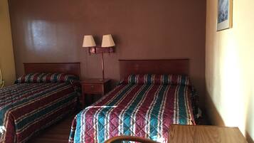 A hotel room with two beds, a nightstand, two wall-mounted lamps, and a wooden chair.