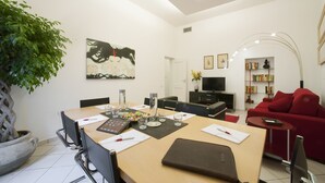 A modern living room with a dining area, a red sofa, a TV, and a bookshelf. - Casa Vittoria (Naples)