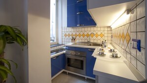 A modern kitchen with blue cabinets, a stainless steel oven, and a tiled backsplash. - Casa Vittoria (Naples)