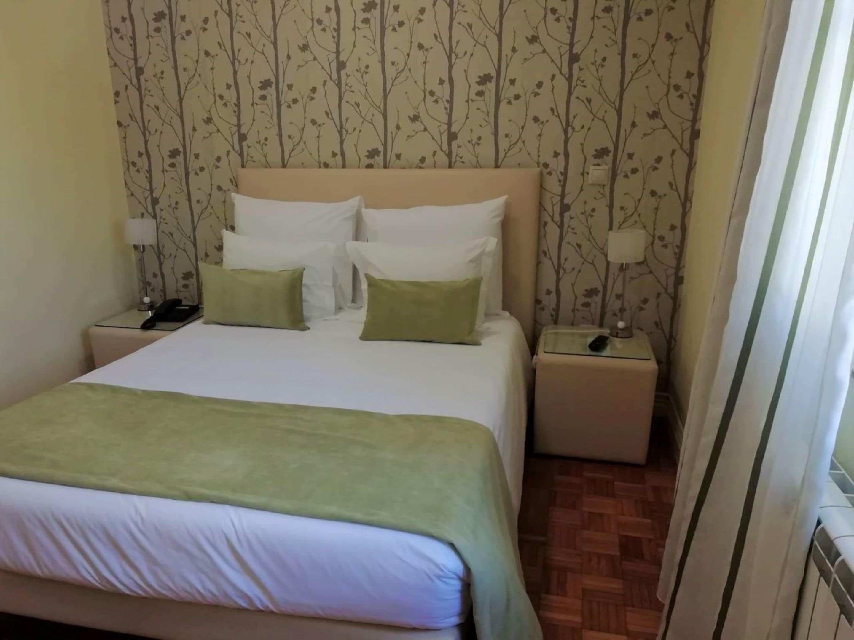 A hotel room with a bed, two bedside tables, and a nightstand.