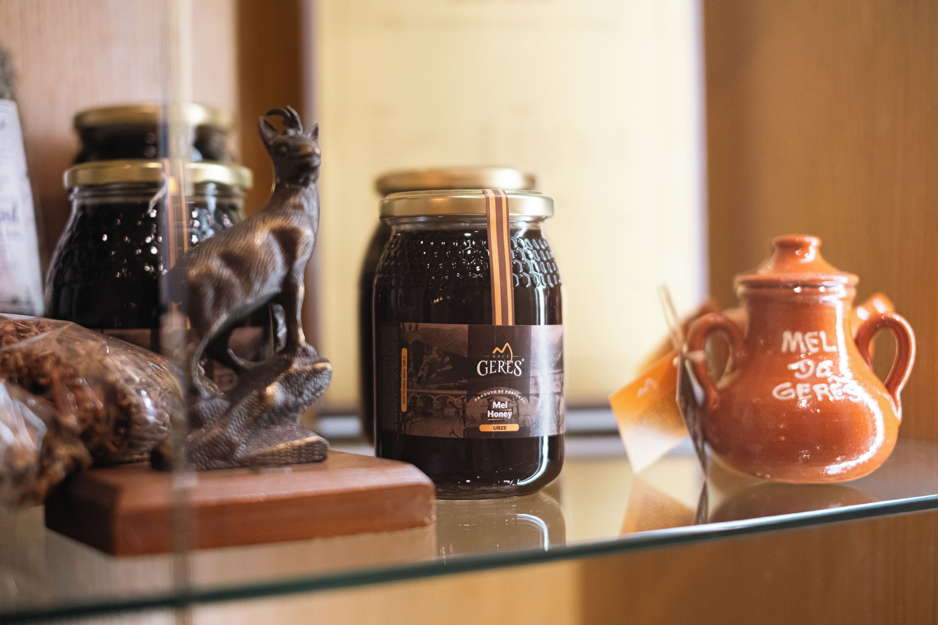 Une vitrine en verre contenant un pot de miel, un pichet en céramique et une figurine.