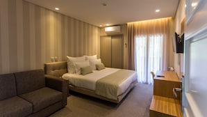 A modern hotel room with a large bed, a sofa, a desk, and an air conditioning unit. - Adelaide Hotel (Terras de Bouro)