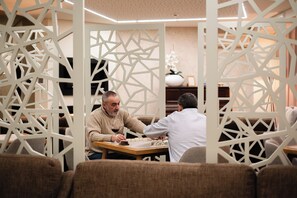 Two people playing a board game at a table in a room with geometric white partitions. - Adelaide Hotel (Terras de Bouro)