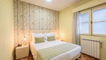 A bedroom with a bed, nightstand, lamp, and radiator.