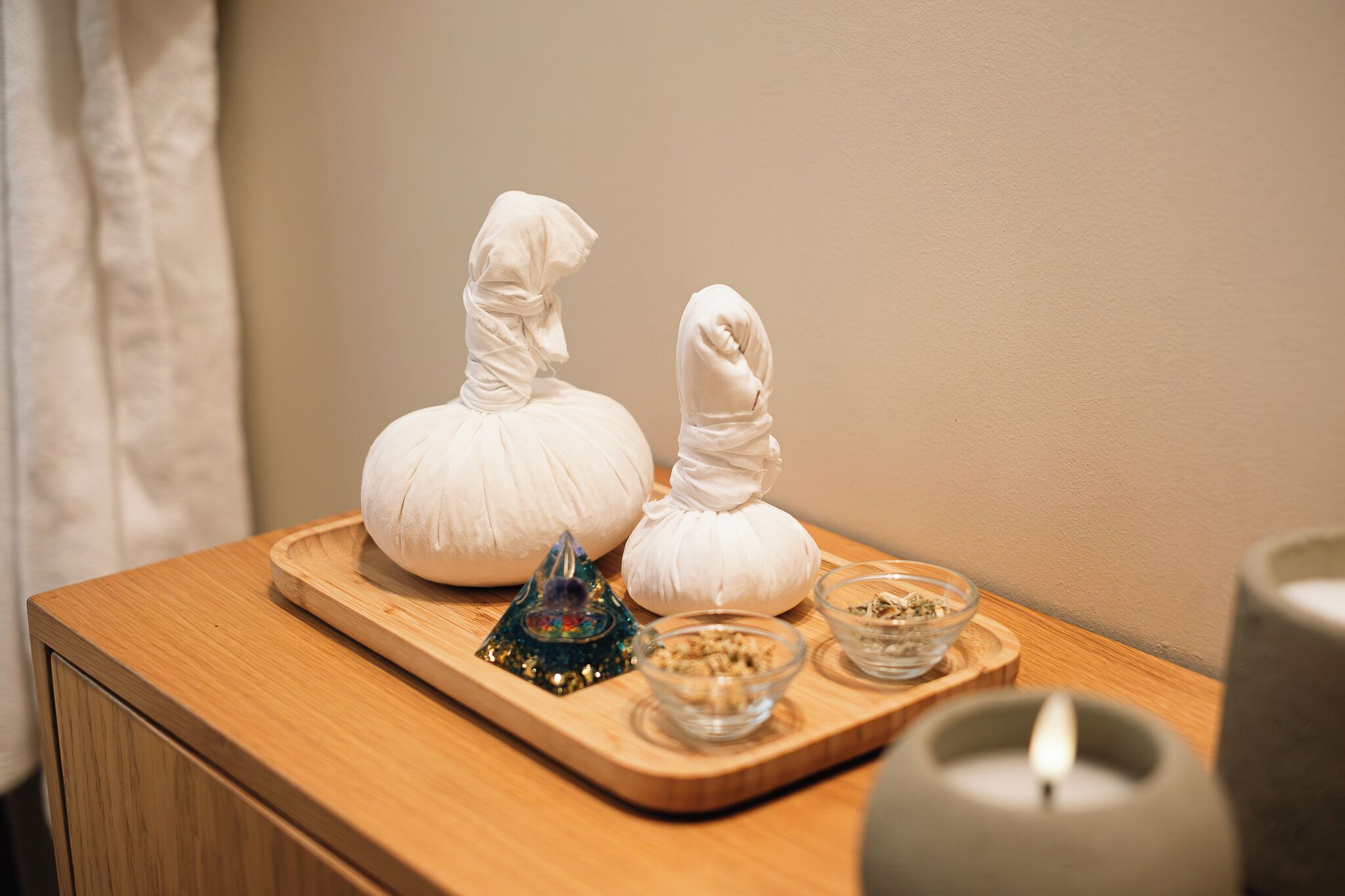 A wooden tray with two white objects resembling dolls, a small decorative item, and two glass bowls with contents on a wooden surface.